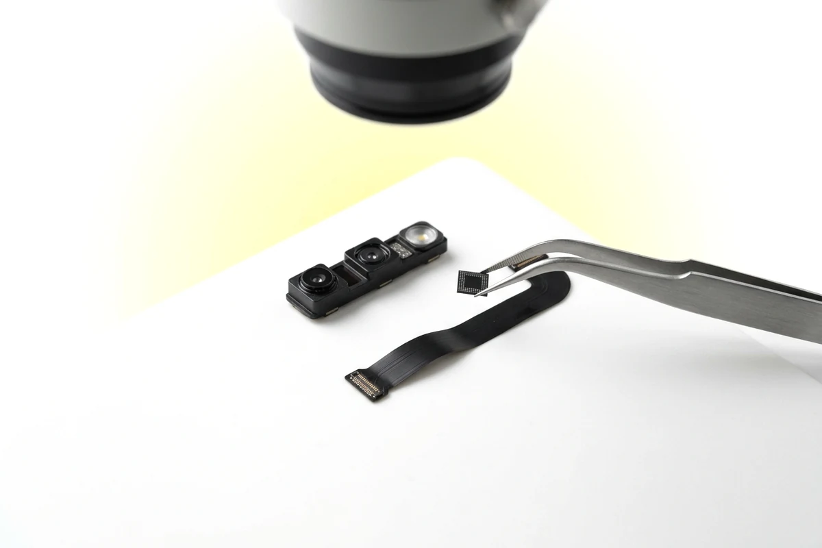 Модуль TrueDepth iPhone 16 Pro Max під мікроскопом під час перенесення мікросхеми на новий шлейф