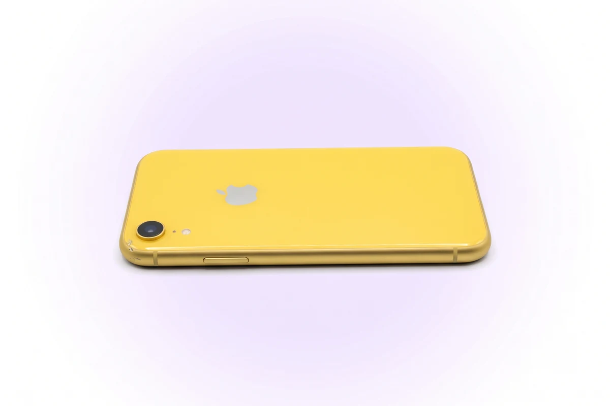 Желтый iPhone XR тыльной стороной вверх с вмятиной на углу рамы рядом с выступом камеры