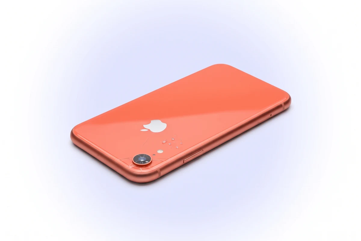 Треснувшее стекло над объективом кораллового iPhone XR и мелкие крошки стекла возле выступа камеры
